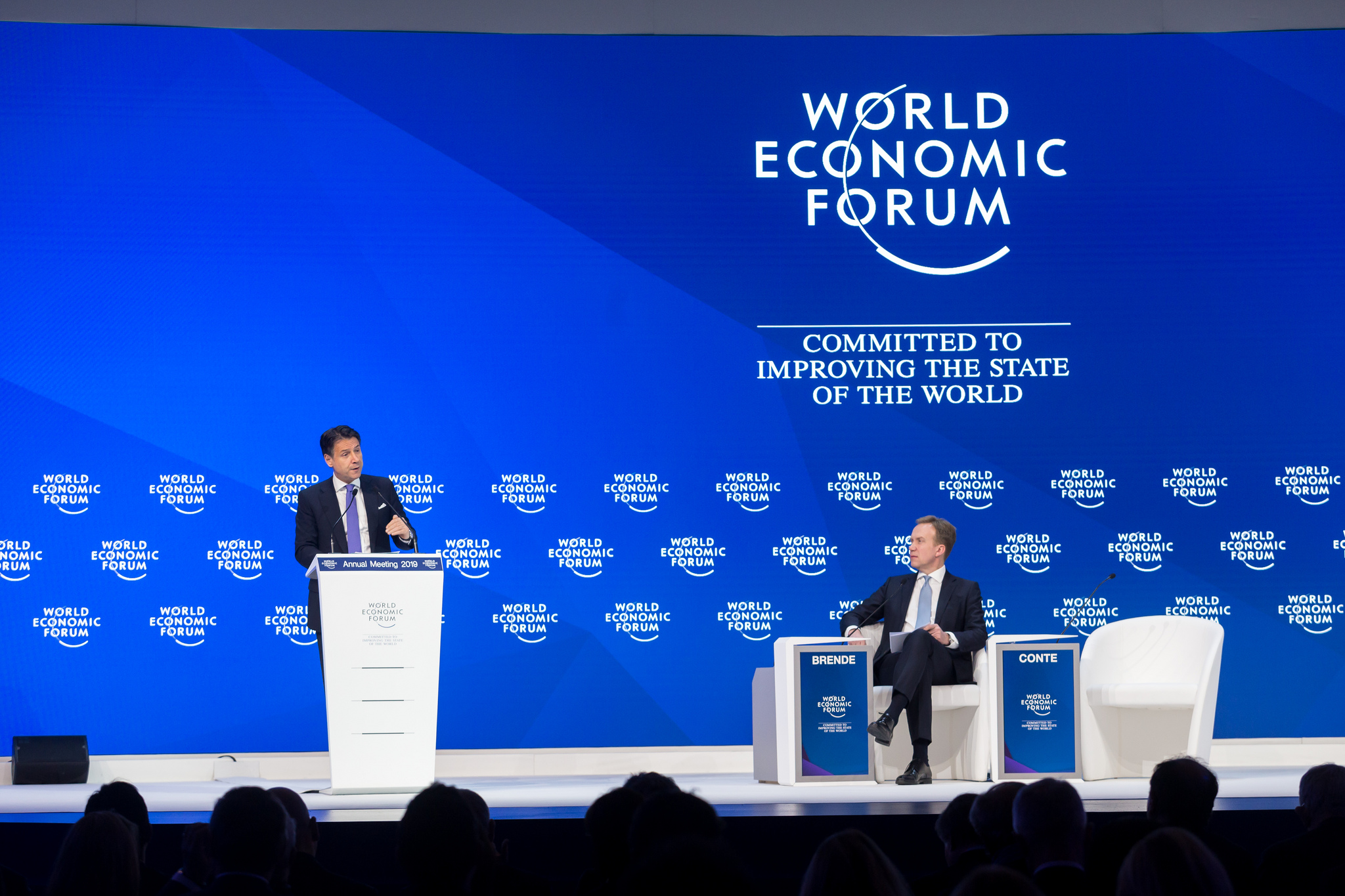 "World Economic Forum - Commited to improving the state of the World" står i bakgrunnen mens Børge Brende sitter og Giuseppe Conte snakker.