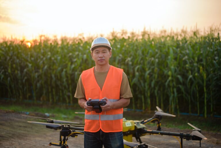 En landbruksarbeider står foran en maisåker med en drone-kontroller. Foran ham er det en drone.