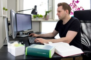 Max Schrems sitter ved en datamaskin og oppslåtte lovbøker